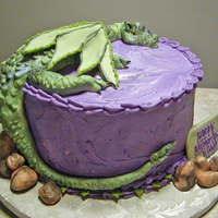 Dragon At Rest Fondant dragon and rocks. Dragon is accented with purple and green luster dust. Cake is iced with purple buttercream swirled with a bit of...