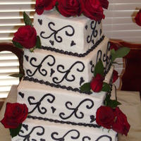 Black On White Sour cream white wedding cake torted and filled with buttercream icing. Hand piped icing scrolls. Fresh/live flowers.