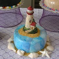 Light House Cake Fifth and final in my series of 5 retirement cakes. Covered in blue marbled MMF and trimmed with graham cracker sand crumbs and sugar sea...