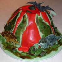 Volcano Dinosaur Cake Carved cake, covered with fondant. Lava RI. Rocks and dinosaurs done with fondant and patchwork cutters. Painted over rocks and volcano...