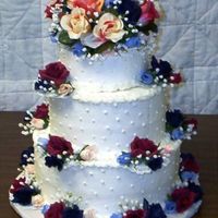 Im001002.jpg This cake was done in buttercream and decorated with Swiss dots and multi colored silk roses with a topper made out of the same flowers.