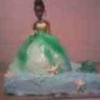 Princess And The Frog Cake. Princess dress is made from barbie cake mold. Pond is made of cake and icing. Frog, stars, and cloth for dress is made out of fondant.