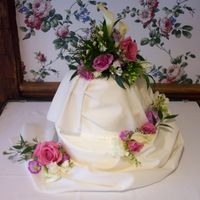 Draped Wedding Cake A draped cake trimmed with fresh flowers. I do not care for fondant, so the drape was real material matched to the soft ivory colored...