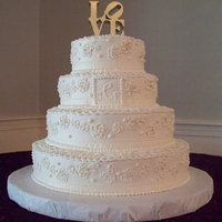 Ivory & Gold Outlined Blossom Wedding Cake All ivory buttercream with outlined blossoms highlited with gold dust. Each tier was wrapped with ivory ribbon. The monogram was piped...