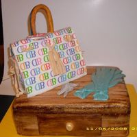 Purse Cake On Table This is a dark chocolate fudge cake with buttercream icing and covered in MMF. The handle and keys and tag are gumpaste and the gloves are...