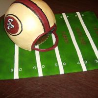 Helmet Helmet iced in ivory buttercream then airbrushed in gold. Helmet stripe and logo were freehanded with buttercream. This was a last minute...