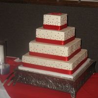 Liz's Wedding Cake French vanilla cake with buttercream icing and real ribbon around bases of each tier. There is one red gumpaste gerbera daisy on top. The...