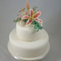 Lily Elegance Dragons and Daffodils Cakes two tier sugarpasted cake with sugar spray of stargazer lily and eucalyptus