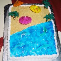 Luau Anniversary Cake buttercream icing,water is tinted piping gel, sand is graham crackers,and i had gummi sharks in the water