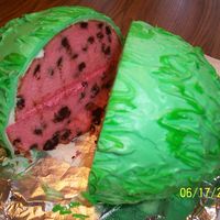 Watermelon White cake with pink food coloring, choclate chips for the seeds. Covered with green fondant, than green buttercream swirls on the top.