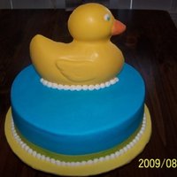 Ducky Baby Shower 12 in. round cake iced in butter cream. Yellow band at the bottom is ribbon. Duck is made out of chocolate using the wilton duck pan as a...