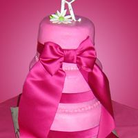 Brandy Buttercream airbrushed fuchsia, fabric from the girls' dresses made into ribbon and bow, fondant daisies.