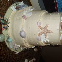 Caryl's Wedding Cake White chocolate and painted fondant shells with a fondant crab. The moss is dyed orential noodle. It's a 3 teired buttercream cake....