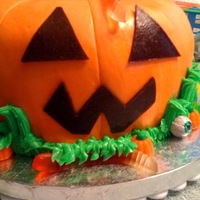 Pumpkin pumpkin cake made from a bundt pan covered in MMF with buttercream grass and store bought candies.