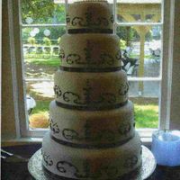 Elegant Black And White Black ribbon accents the tiers of this buttercream wedding cake. The black scrollwork matches the train of her wedding gown. They loved the...