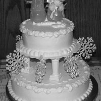 Snowflake Wedding Cake 10" and 6" cakes iced in buttercream. White sparkles around snowlike edges. Snowman and snowmam are Christmas ornaments (I added...