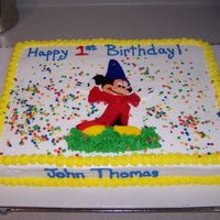 Mickey Mouse Cake buttercream icing with handpainted fondant mickey mouse. confetti sprinkles. grass under mickey's feet is buttercream also.