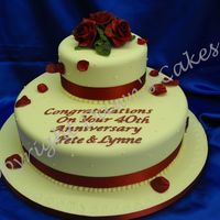 Ruby Wedding Anniversary Stacked Sponge cake iced in ivory sugarpaste with hand made roses in burgundy flowerpaste and scattered petals