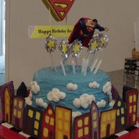 Up, Up, And Away! This is a double round layer on top of a square, iced in buttercream. The clouds are piped on. Buildings are made from candy melts. The...