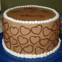 Chocolate Anniversary 8 inch round with chocolate buttercream. Hearts on the side were made with an impression from a cookie cutter. The top says Happy 25th...
