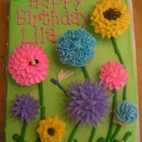 A Garden Party Cake Flower cupcakes, with fondant bees and picket fence