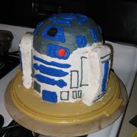 R2D2 Four 8-inch cakes stacked and carved (2 white and 2 chocolate). The legs are rice crispy treats. Decorated in all buttercream.