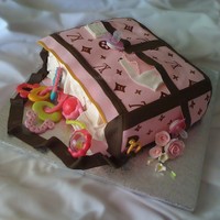 Louis Vuitton Diaper Bag Cake Fondant covered, w/ fondant accents. They two toys and the two pacifiers are store bought. The LV patterns are hand painted using brown...