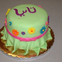 Dress Cake This was for a girl who loves Gerber daisies, and she's also half Egyptian. She wears a necklace with her name in Arabic, which is on...