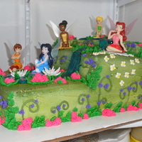 Tinkerbell Buttercream frosting with airbrushed green, water is made from colored piping gel, fairies are cake topper