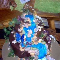 Waterfall Cake Cake was for a special church function. 2.5 tiers stacked, iced with choco bc icing, rocks are fondant, foliage/flowers are silk,...