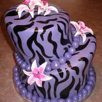 Purple Zebra Two tier topsy turvy cake covered in MMF and painted zebra stripes. Flowers are gumpaste.