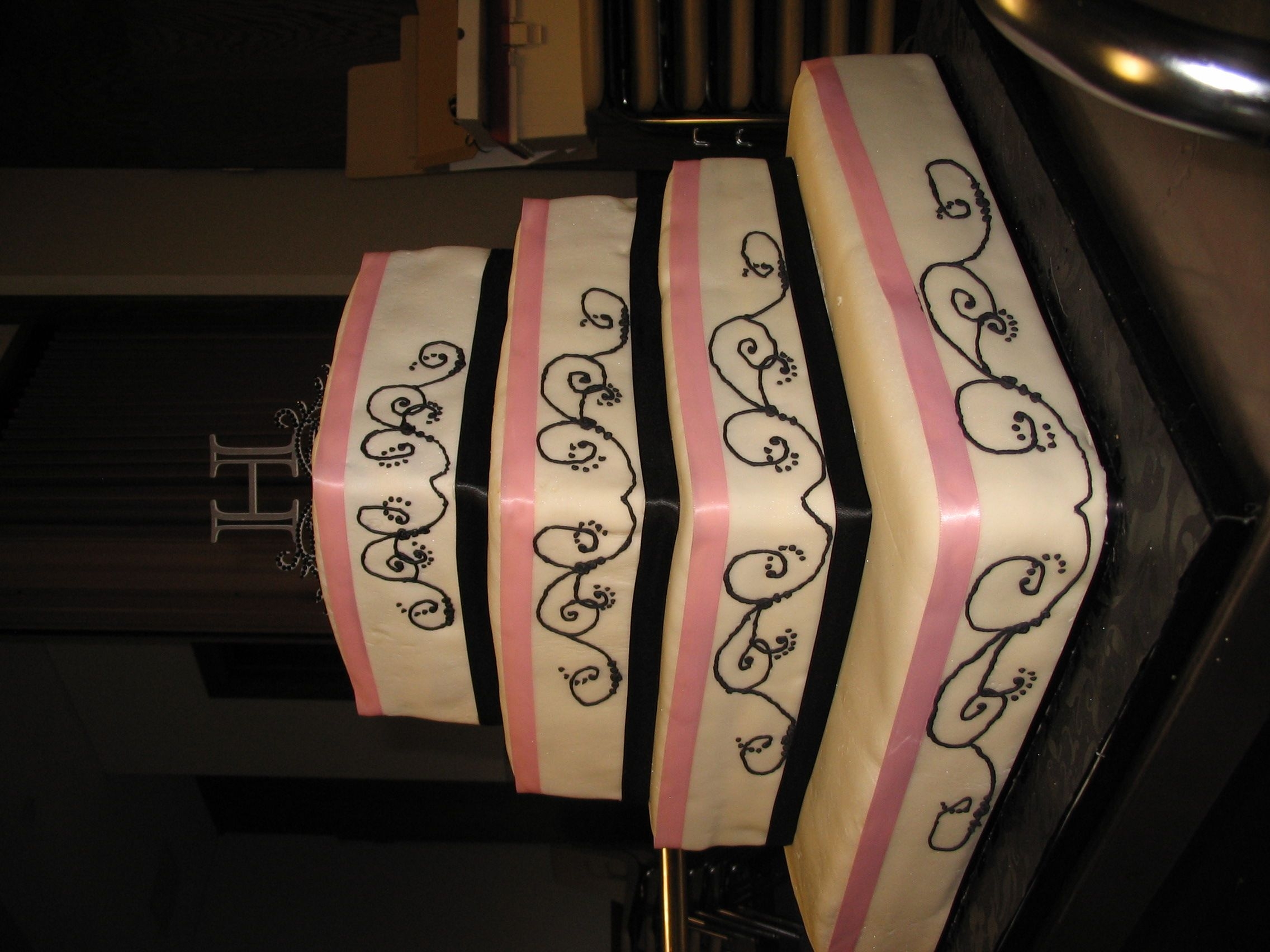 Ashley's Wedding Cake Four layer wedding cake, 16", 12", 10", 8", black and pink ribbon and black piping.