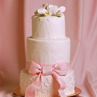 Pink Linen Bow A fondant ribbon and bow with a linen texture tied around a buttercream cake topped with gumpaste orchids.