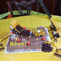 Construction Chocolate cake, with shredded brownies for dumping. Candy rocks for border. Toys and cone candles to complete the scene.