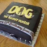 Dog The Bountyhunter 10" chocolate cake iced with IMBC, covered with chocolate fondant and airbrushed black with a chocolate transfer for the logo. Dog...