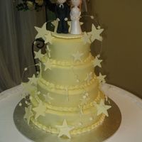 Wedding Cake Four tier mud cake covered with white ganache and white chocolate stars, topped with sugar bride and groom.