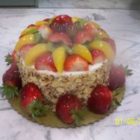 Any Ocassion Fruit Cake Yellow with whip topping icing & garnished with toasted almonds, fresh peaches, grapes, kiwii, and strawberries