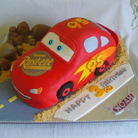 Cars Lightning Mcqueen First car (kindof) cake. Not as easy as I'd hoped! All fondant decorations, cookie crumb sand, fondant covered cookie wheels, finished...