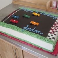 Race Car Cake Chocolate cake with raspberry filling and italian buttercream. Cars were made in a chocolate mold with fondant and painted.