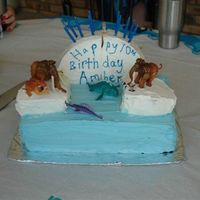 Ice Age Cake Sheet cake on bottom, iced like water, with a round cake cut in pieces and iced white for icebergs. The figurines were just toys from...