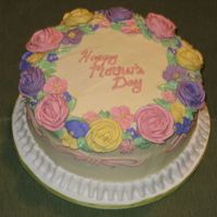 For Mom Flowers done with royal icing. Ruffle border and iced in buttercream. Cake is three layer white with strawberry filling.