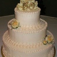 50Th Anniversary 3 tier buttercream iced in ivery, hand piping in a deeper ivory, yellow silk roses. "50" made from gumpaste and painted with gold...