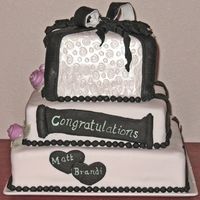Matt-Brandii1.jpg 3 tier cake, with different 'celebration on each side.Fondant covered, luster dusted top layer, fondant bow, heart and congradulations...