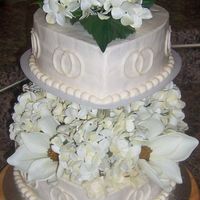 Ivory Heart-Shaped Wedding Cake This is a wedding cake for a couple that wanted a heart shaped cake with entwined rings incorporated in the cake. The flowers used on the...