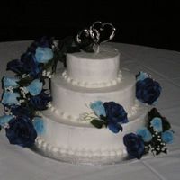 Blue Rose Cake 3 tier vanilla bean cake, raspberry cream filling, and chocolate with banana filling. Blue silk roses cascade at customer request.
