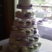 Cupcake Tower My first cupcake tower. Various shades of purple gumpaste roses on the topper cake and around the cupcakes.
