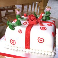 Santa Helpers Chocolate cake covered with white fondant, fondant bow and gumpaste elfs.