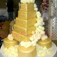 Gold Wedding Cake 5 tiered wedding cake. Top 2 tiers are strawberry with coconut buttercream covered in mmf and airbrushed gold. Bottom 3 tiers are dummy...