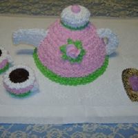 Tea Pot Cake All iced in buttercream. Top of tea pot and tea cups are cupcakes. Molded candy mints on doilie.