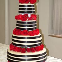 A Formal Cake The cake was designed to match the bridal party. MMF covered with black satin ribbons with fresh roses. 16, 12, 8 & 6 inch tiers.